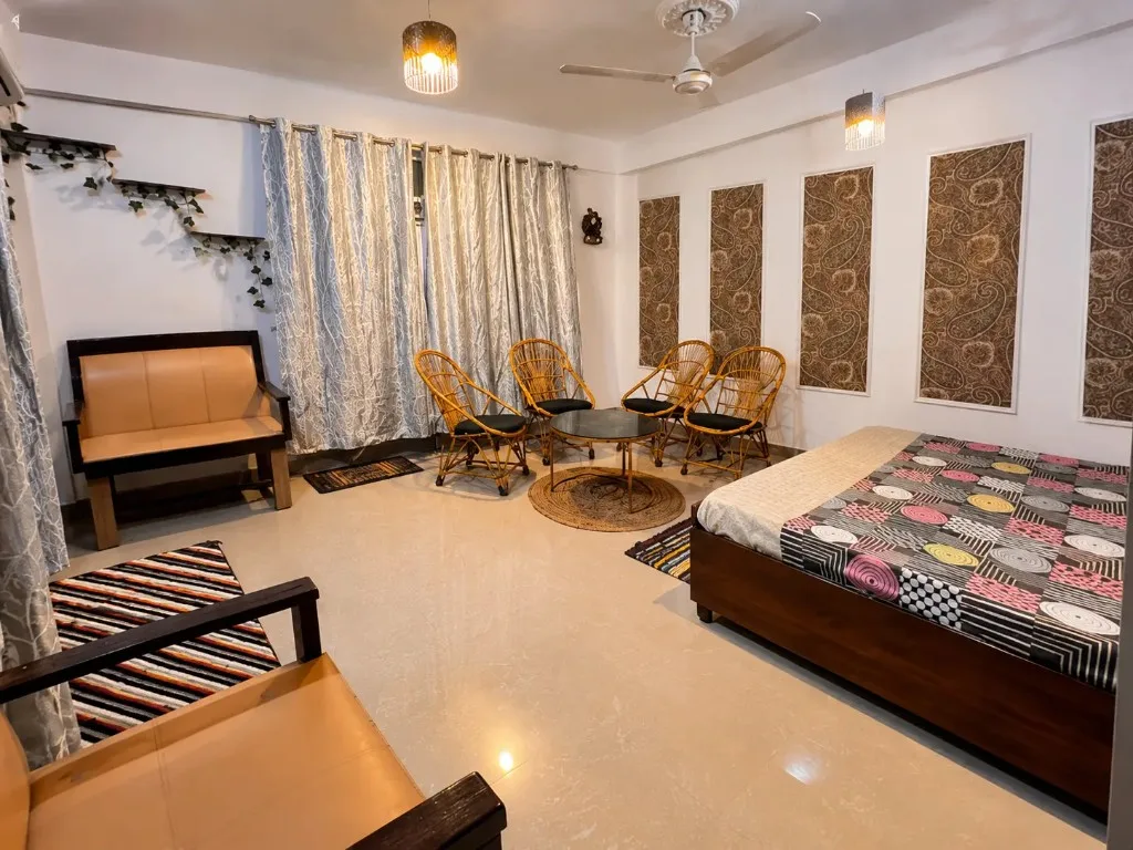 Studio bedroom with a bed, rattan chairs, and a small seating area