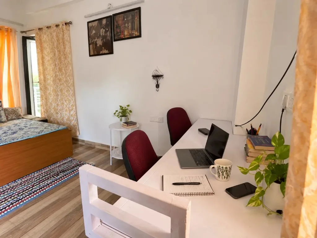 White desk with a laptop and chairs in a bedroom workspace